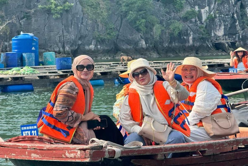 Muslim women on bamboo boat in Halong Bay Three Muslim women in colorful attire and life vests smiling during a bamboo boat ride in Halong Bay