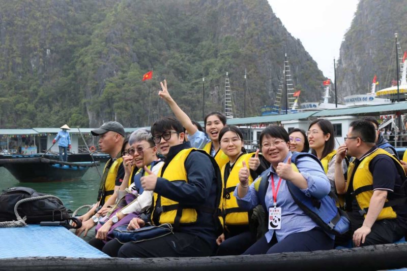 Bamboo boat tour with tourists in Halong Bay Group of tourists wearing life jackets enjoying a bamboo boat ride in Halong Bay near limestone karsts