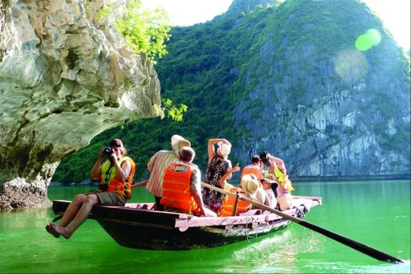 Photographers on bamboo boat in Halong Bay Group of tourists taking photos on a bamboo boat ride near a dramatic cliffside in Halong Bay