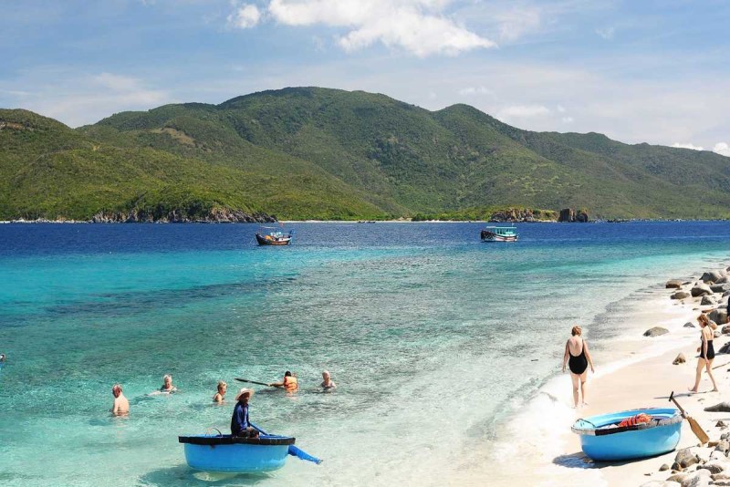 Beachfront Relaxation and Swimming at Tranh Beach People swimming and relaxing on the sandy beach with calm waters and beach facilities at Tranh Beach.