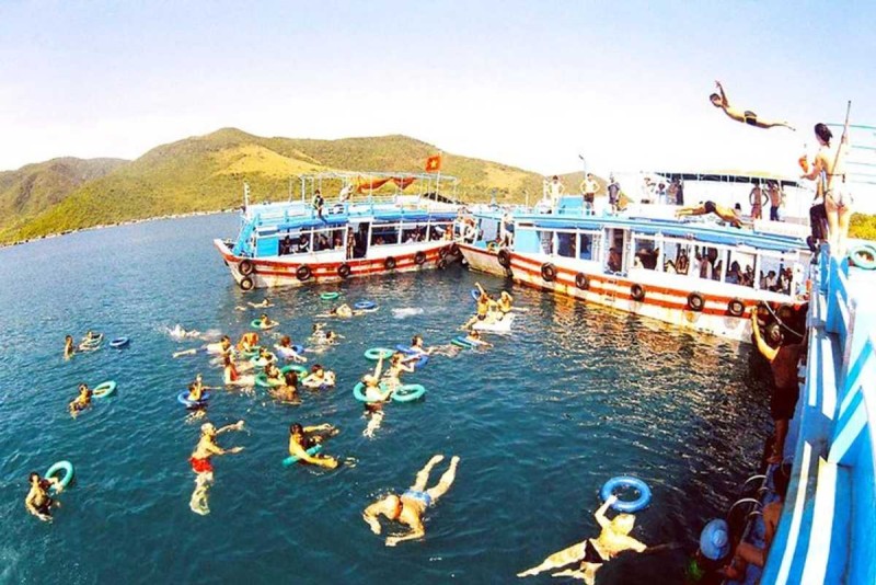 People swimming and enjoying the boat cruise at Hon Mot Island Nha Trang with two boats in the background
