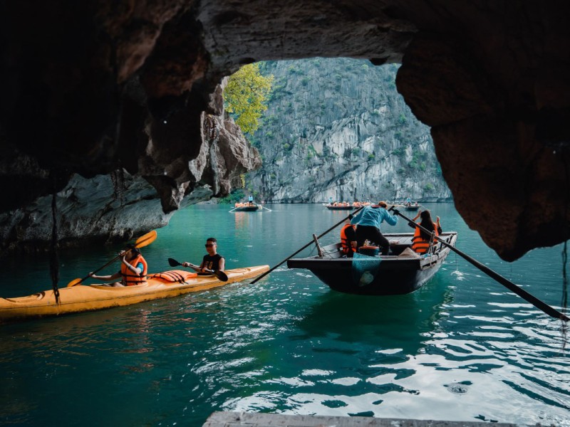 Bright Cave and Bamboo Boats in Lan Ha Bay Tourists paddling through Bright Cave in bamboo boats with natural light illuminating the limestone cave interior.