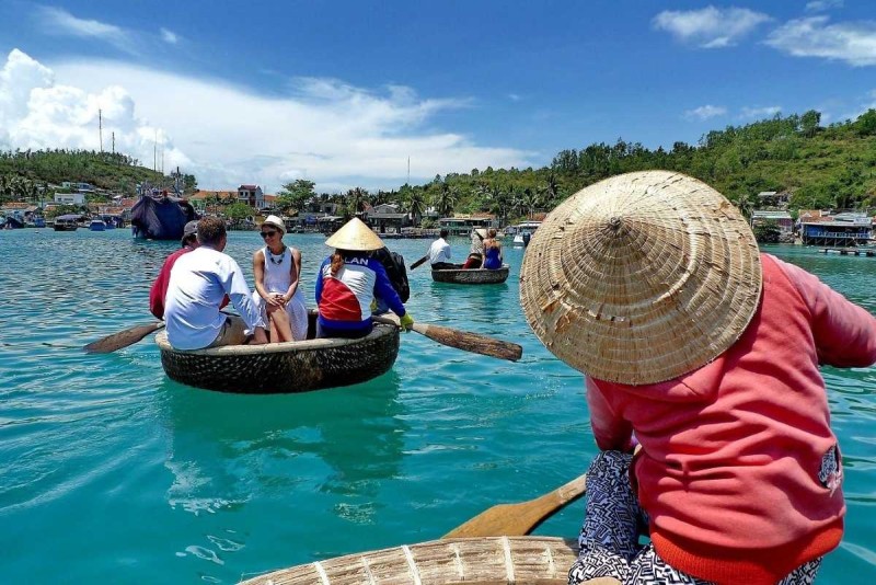 Cruising on Cai River in traditional Vietnamese basket boats near local fishing villages under blue sky