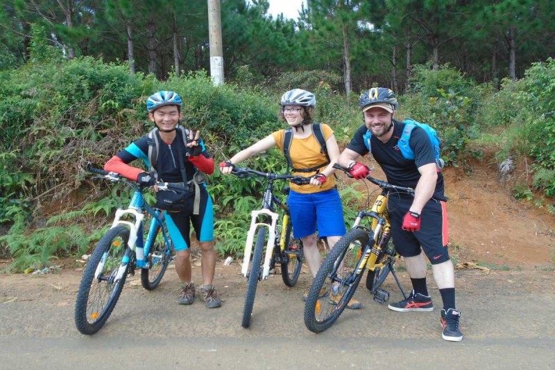 Three cyclists posing with mountain bikes on a countryside trail in Nha Trang during a group ride