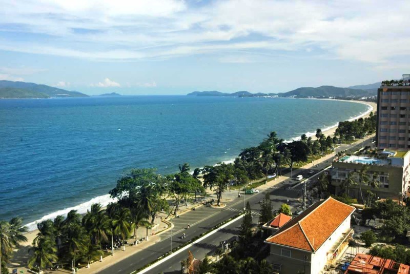 Cyclo ride along the scenic beachfront road in Nha Trang with palm trees and clear blue sea