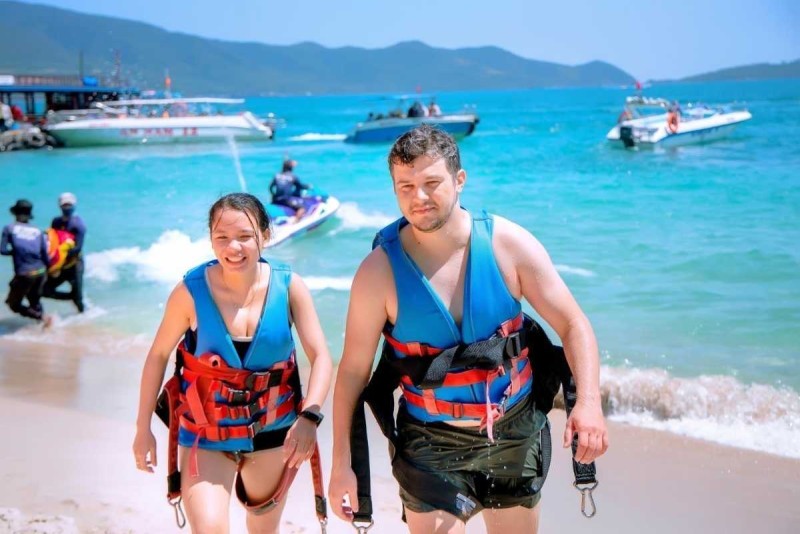 Exciting Water Sports and Swimming at Tranh Beach Visitors enjoying water sports activities like jet skiing and swimming at Tranh Beach with vibrant blue sea.