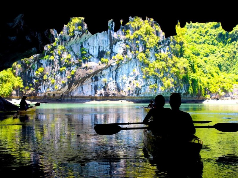 Exploring Bright Cave by Bamboo Boat in Lan Ha Bay Scenic bamboo boat ride inside Bright Cave, offering a glimpse of Lan Ha Bay’s lush greenery and limestone karsts.