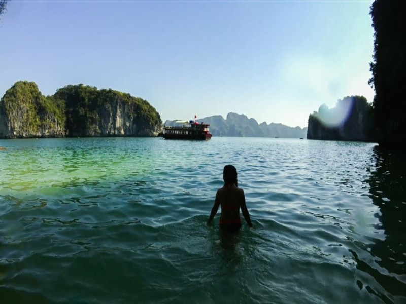 Exploring Halong Bay’s Waters Travelers exploring the clear waters of Halong Bay with iconic cliffs in the backdrop.
