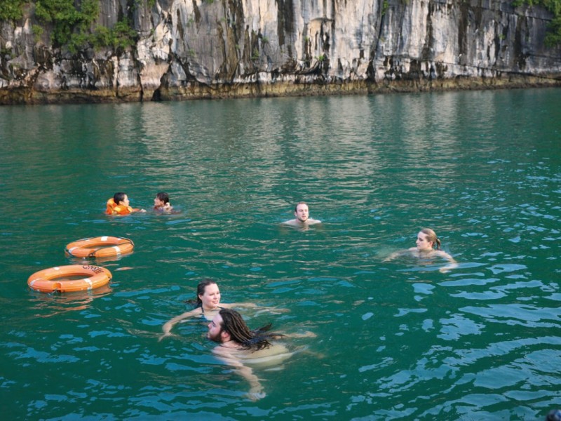 Family Fun Swimming in Halong Bay A family enjoying a fun swim in the calm waters of Halong Bay with scenic surroundings.