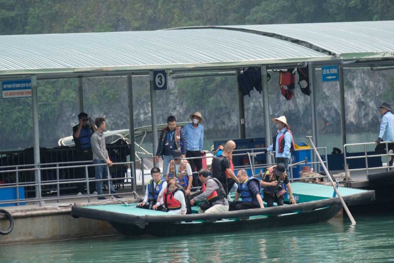 Tourists boarding bamboo boats at Halong pier Travelers preparing to board bamboo boats at a dock in Halong Bay with staff assisting