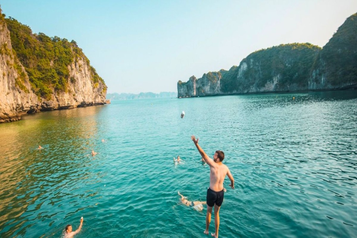 A man jumping into Halong Bay’s emerald waters from a cruise boat, ready for an adventure.