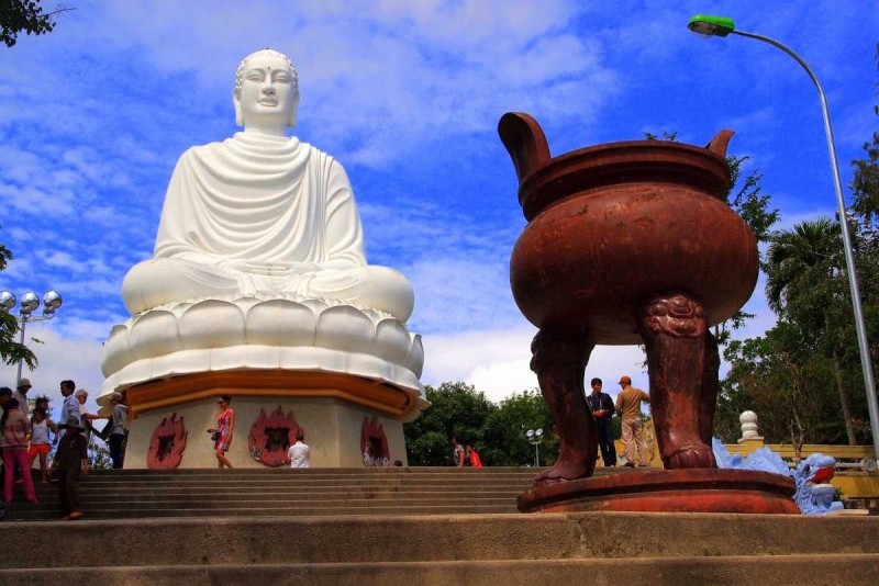 Long Son Pagoda statue and incense burner The white Buddha statue seen behind a large traditional incense burner and stairs at Long Son Pagoda