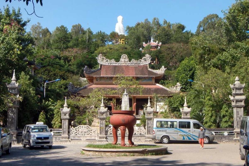Temple grounds with visitors at Long Son Pagoda Visitors walking on temple grounds surrounded by trees and statues at Long Son Pagoda