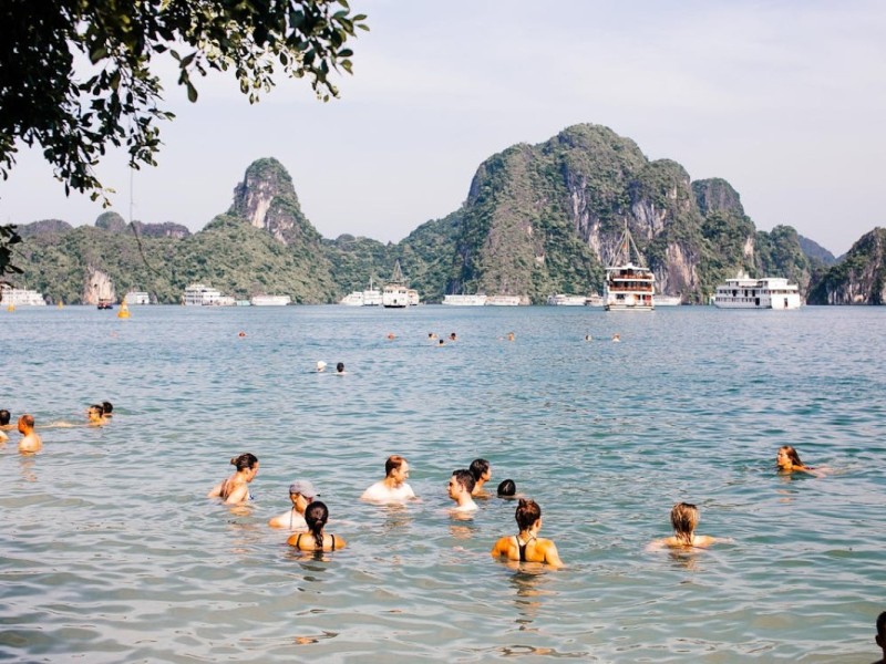 Refreshing Swim at Halong Bay Beaches Visitors enjoying a cooling swim at Halong Bay’s sandy beaches under a bright sky.