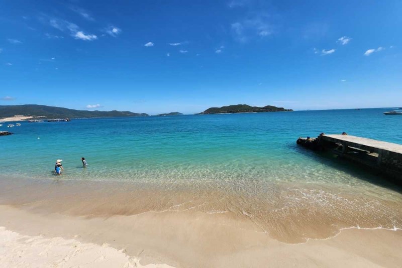 Sunny Day Swimming at Tranh Beach Nha Trang Visitors enjoying a sunny day swimming and relaxing on the sandy beach with clear water at Tranh Beach Nha Trang.