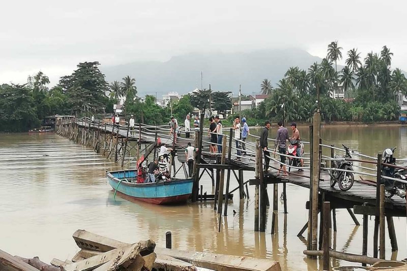 Wooden bridge over Cai River with people and boats, showing swimming spots in Cai River Nha Trang