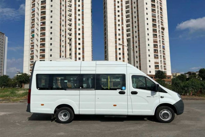 Side view of shuttle van for transfer from Nha Trang City Centre to Cau Da Port White shuttle van parked near residential buildings for transfer to Cau Da Port