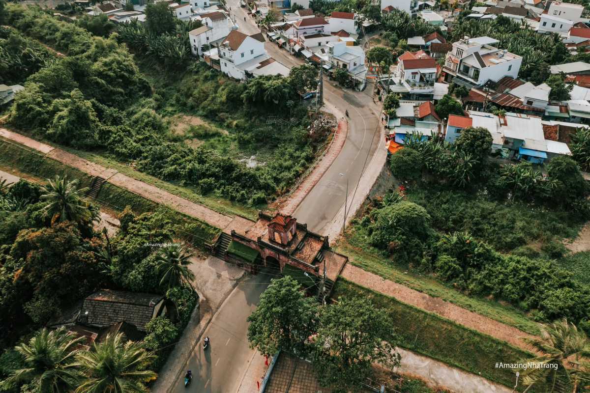 Aerial view of Dien Khanh Citadel showing red-tile gate, curved road, and residential area.