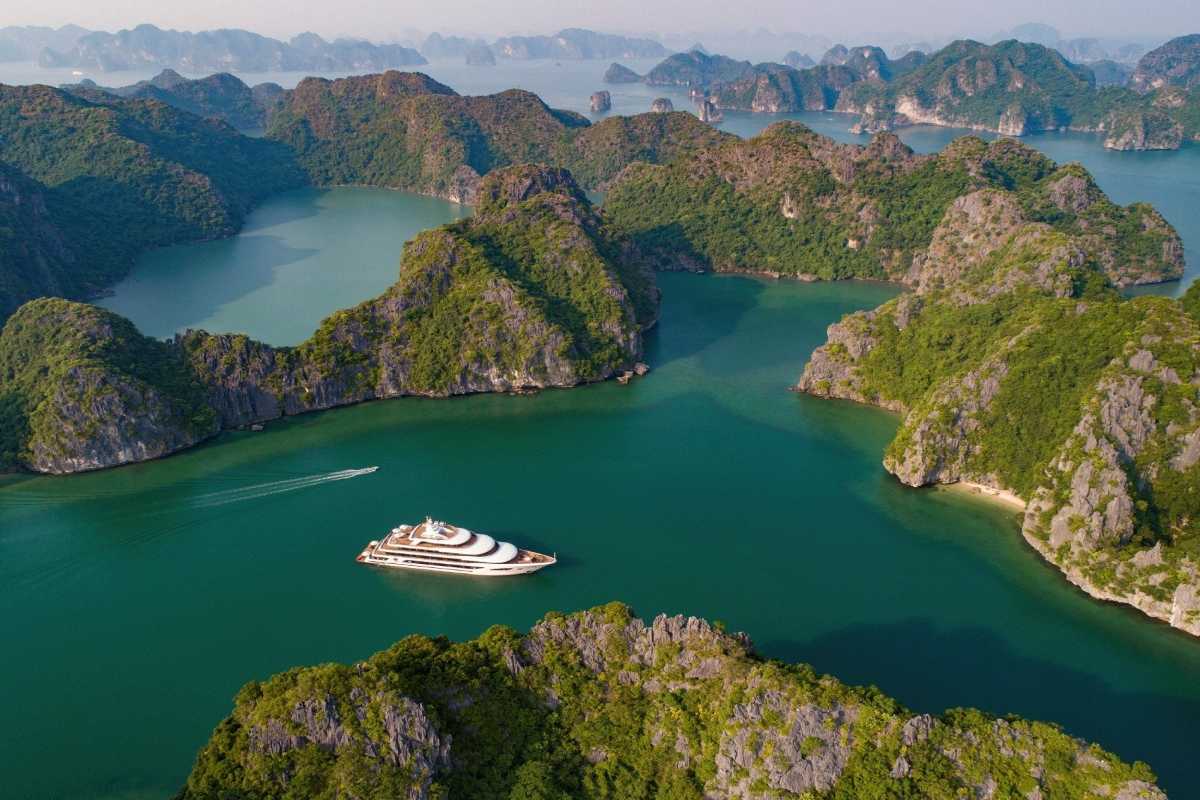 Panoramic view of Ba Ham Lake Halong Bay with multiple boats navigating emerald waters among limestone islands.