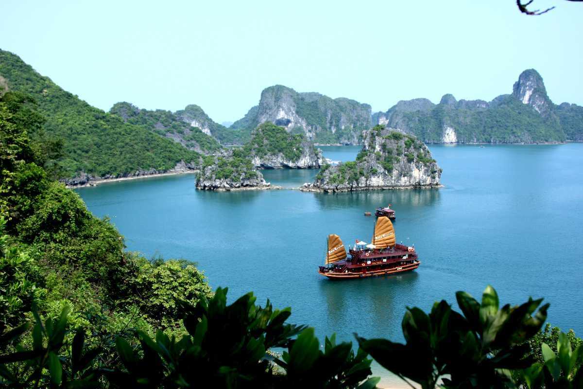Traditional wooden junk boat cruising the calm waters of Ba Ham Lake Halong Bay surrounded by limestone islands