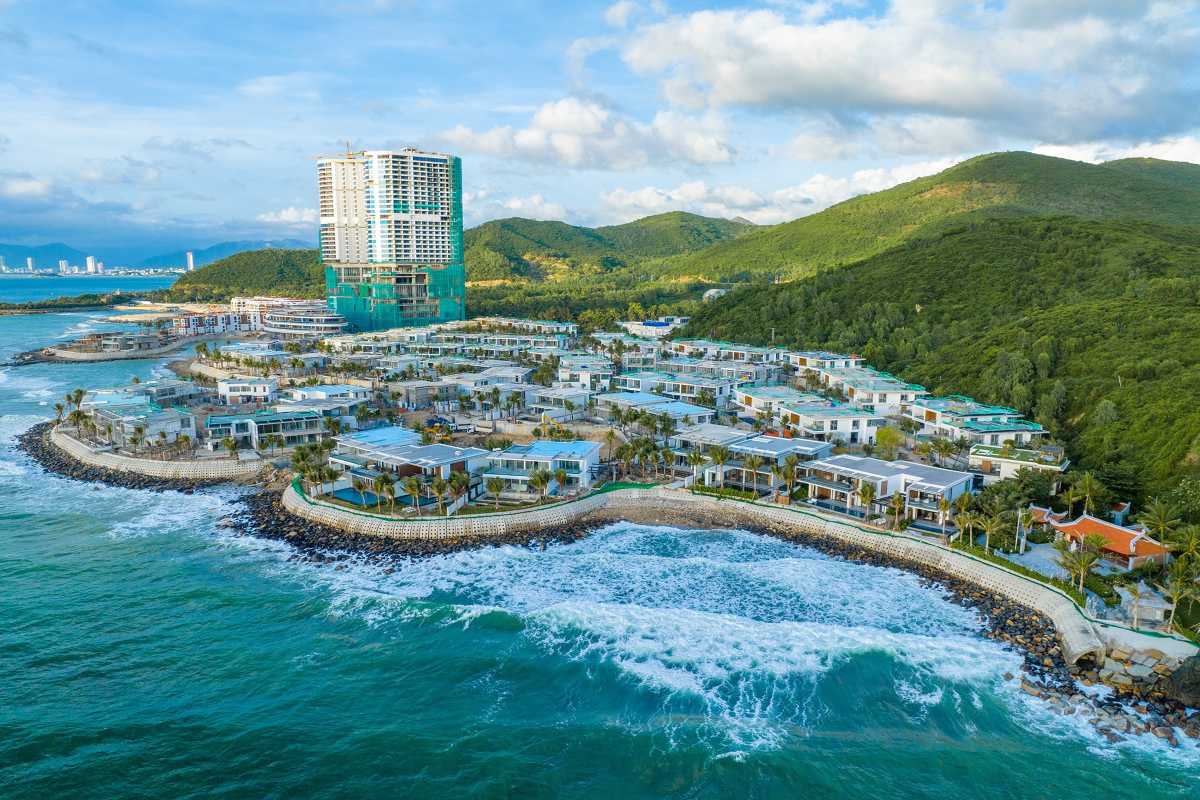 Coastal view of Bai San Beach with modern resort buildings and lush green hills in Nha Trang