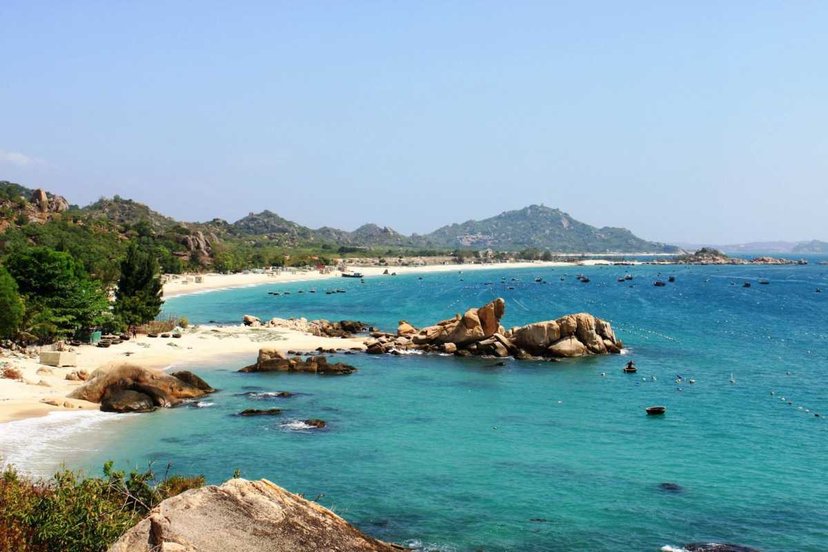 Tour boats cruising between limestone karsts in the clear waters of Bai Tu Long Bay near Quan Lan Island