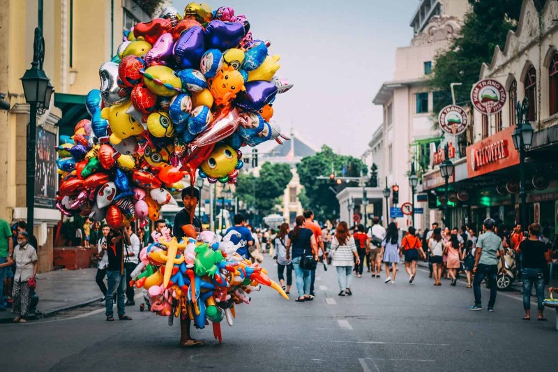 Balloon Vendor on Hanoi Walking Street A vendor selling colorful balloons in the bustling walking street of Hanoi French Quarter, surrounded by tourists.