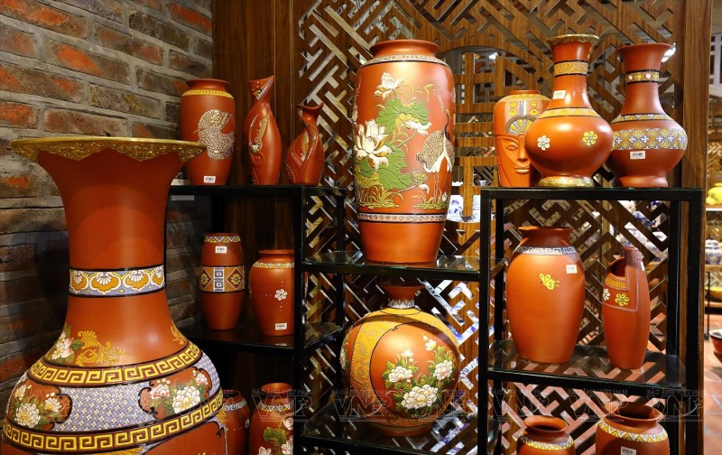 Traditional red and gold ceramics displayed in Bat Trang Pottery Village, showcasing intricate craftsmanship and design.