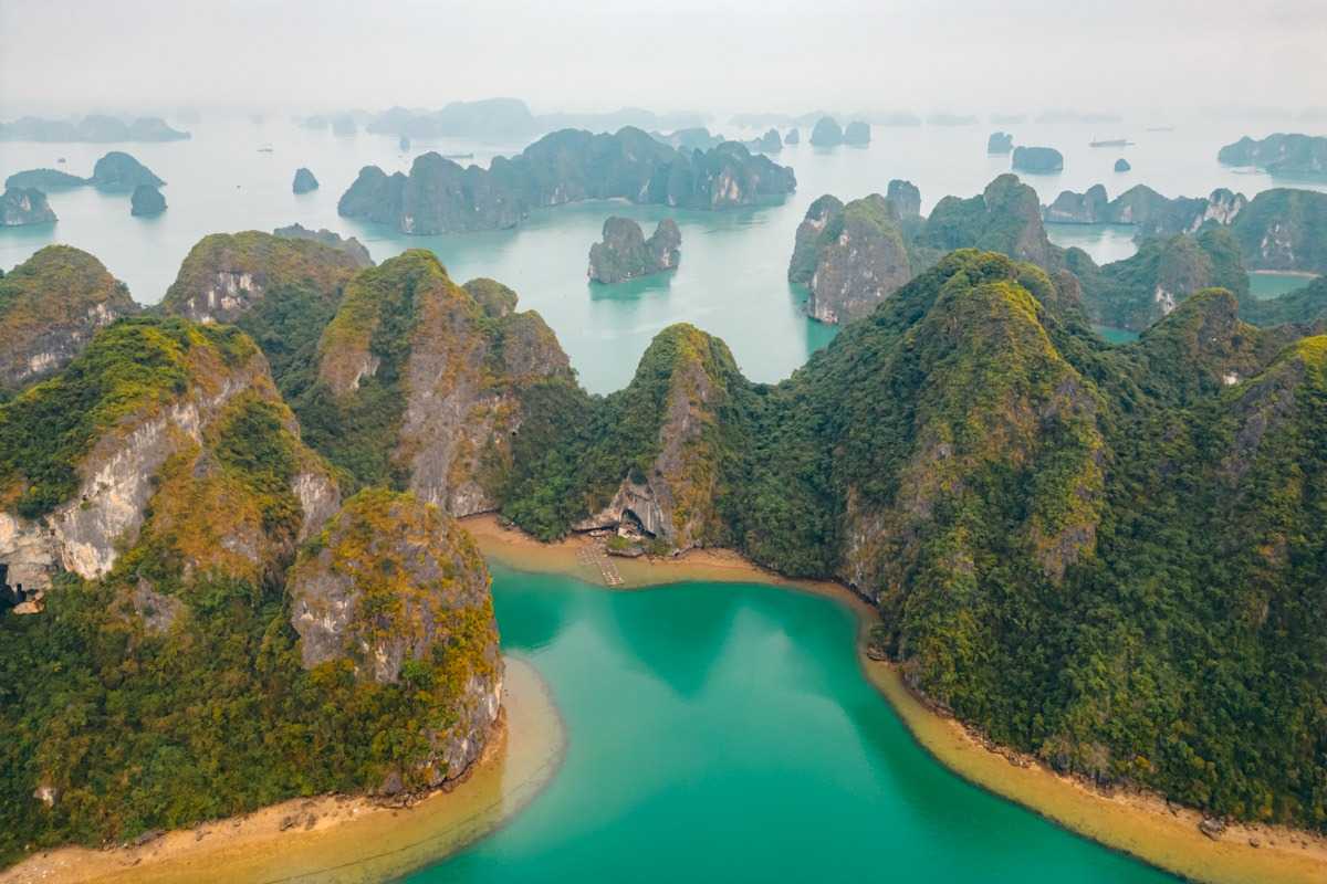A tranquil boat ride on the emerald waters near Bo Nau Cave Halong Bay, surrounded by lush green mountains.