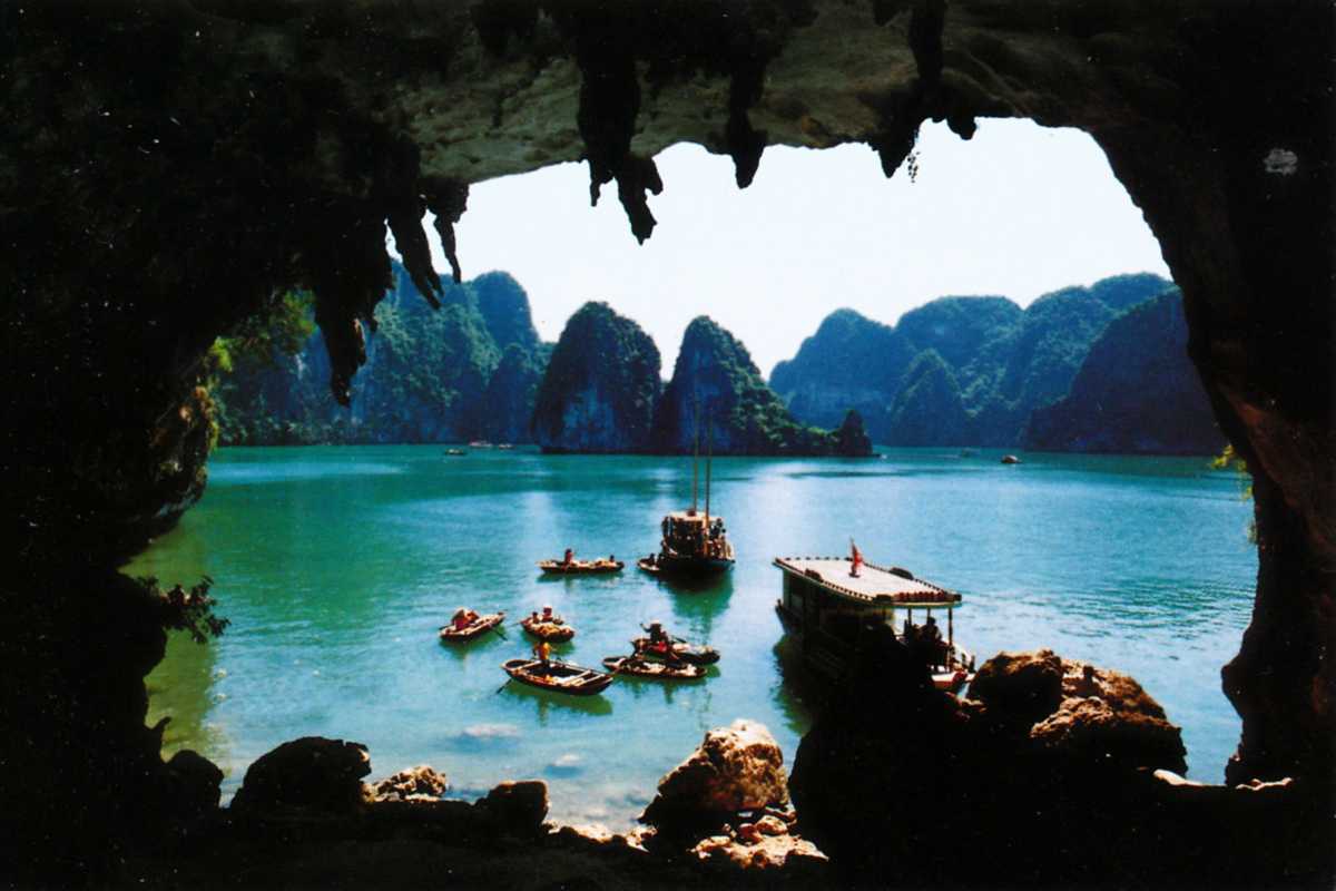 Bo Nau Cave Halong Bay entrance framed by towering limestone cliffs and surrounded by calm waters.