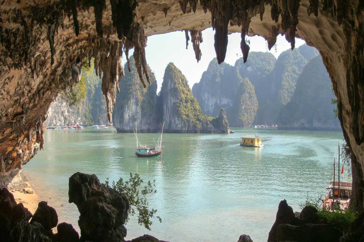 Bo Nau Cave Halong Bay featuring towering limestone peaks and traditional boats floating in calm waters.