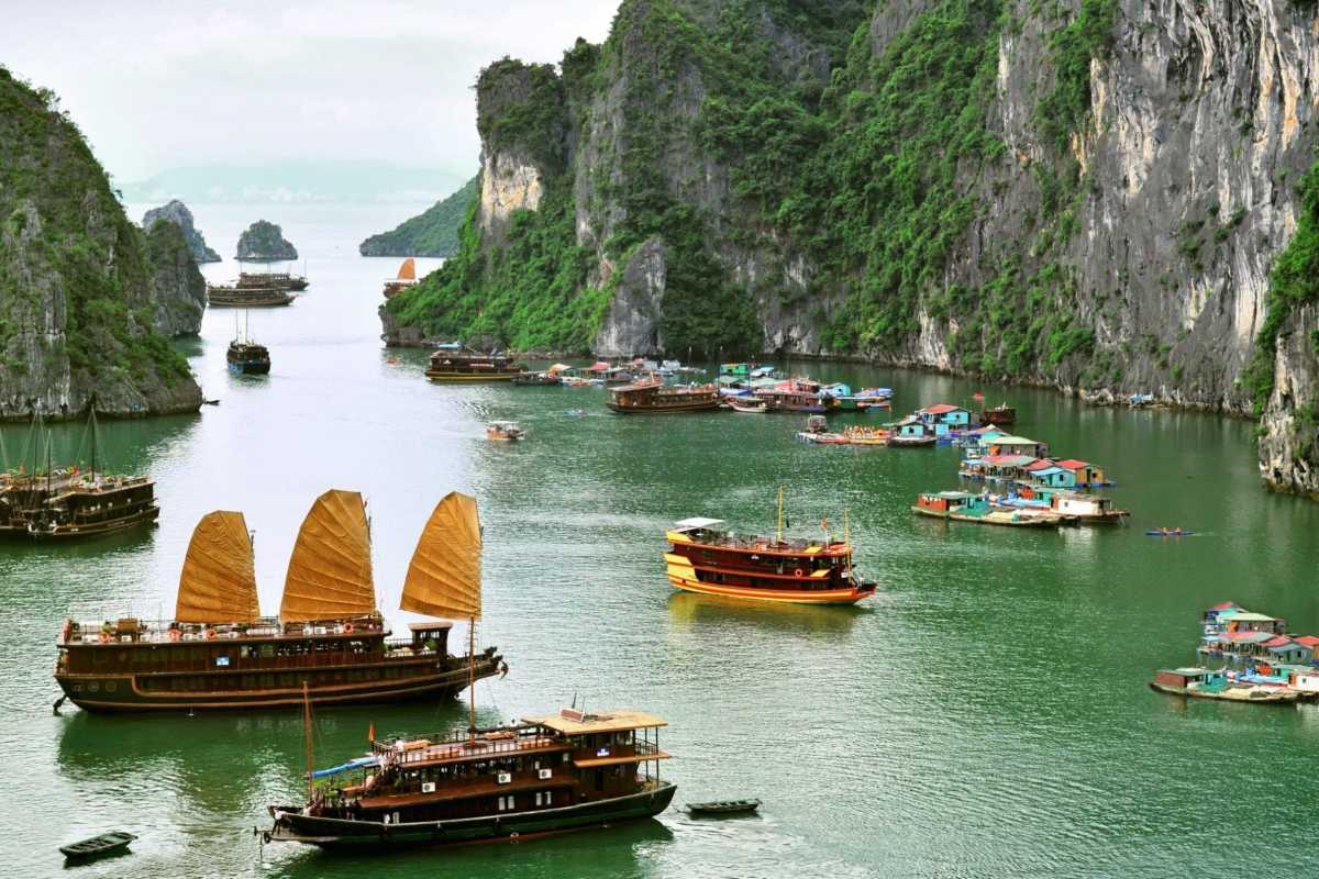 A picturesque boat journey through Bo Nau Cave Halong Bay, with towering peaks and clear waters surrounding.