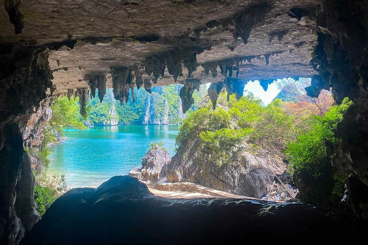 A stunning view from Bo Nau Cave in Halong Bay with towering limestone formations and a passing boat.