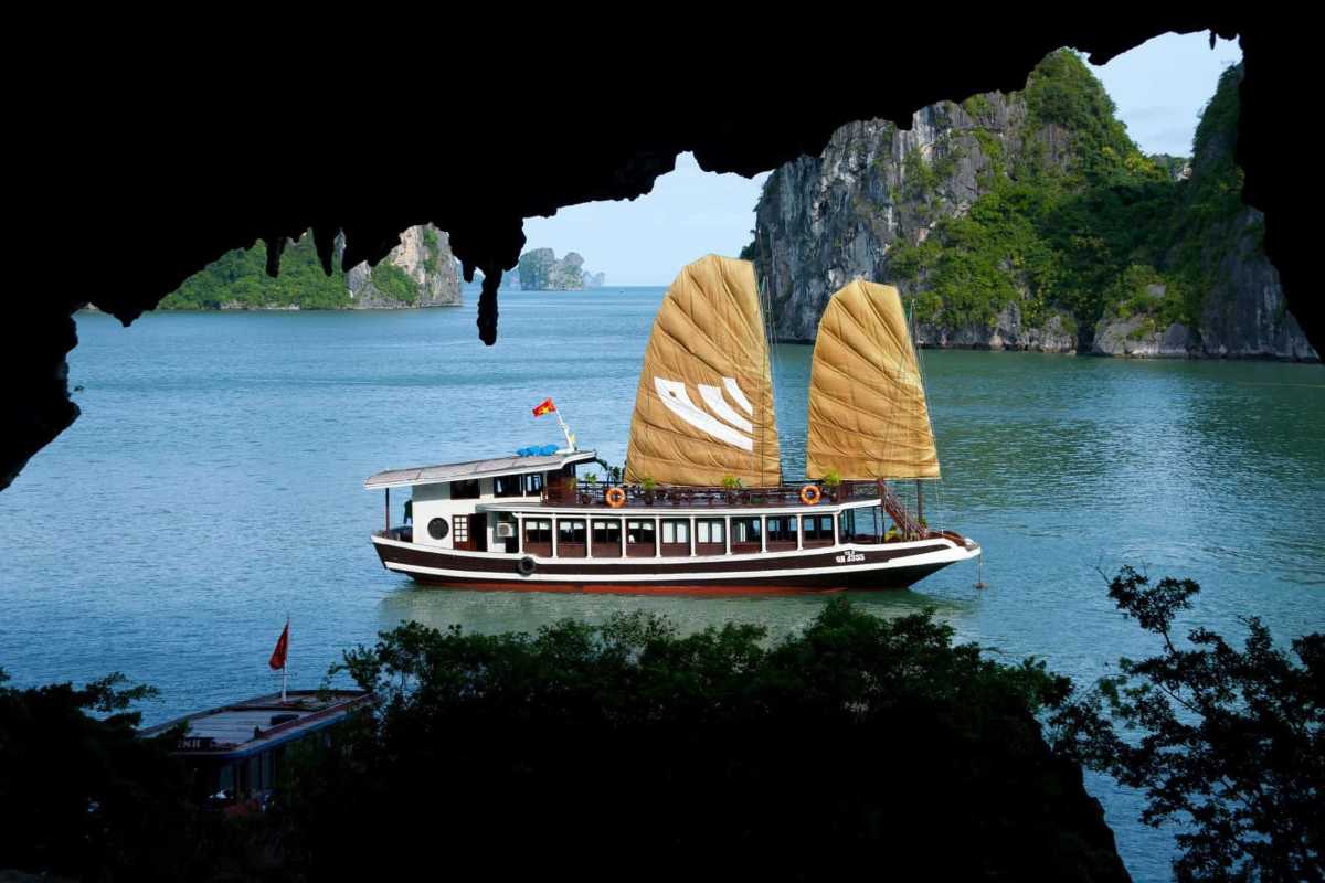 Traditional boats on the emerald waters of Bo Nau Cave Halong Bay with lush green karsts in the backdrop.