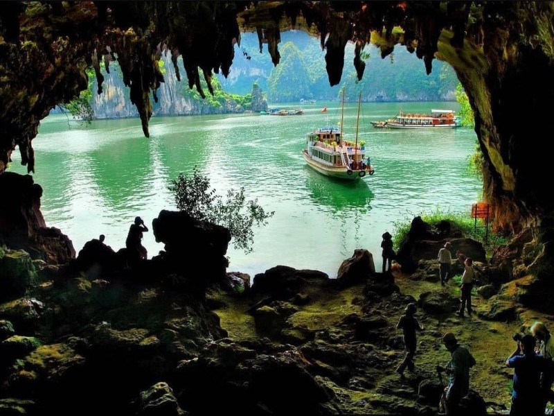 A boat entering Trinh Nu Cave in Halong Bay, seen from inside the cave with limestone formations around.