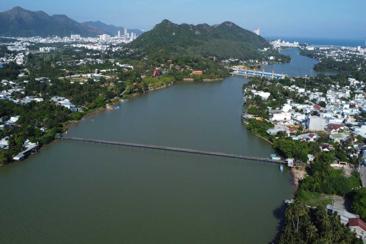 The Cai River curves through lush hills with Nha Trang city in the background, framed by calm water and green slopes.