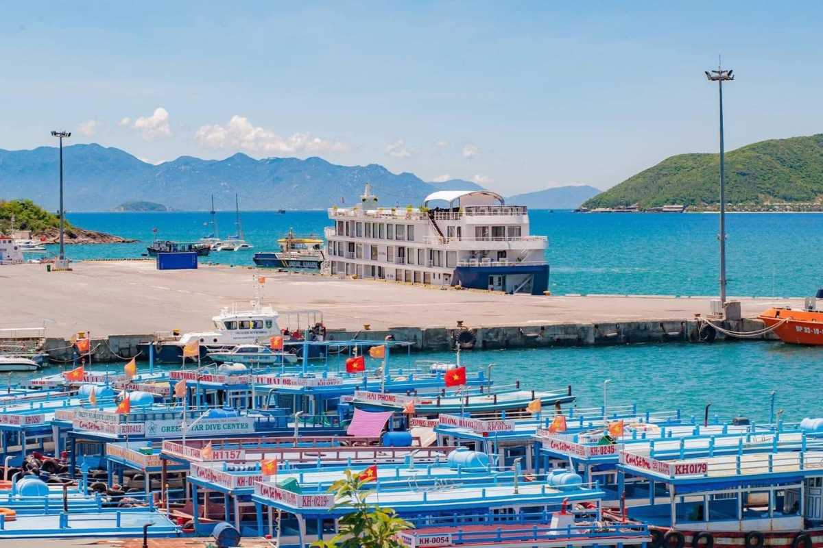 Colorful tour boats docked at Cau Da Port Nha Trang with blue waters and mountain backdrop.