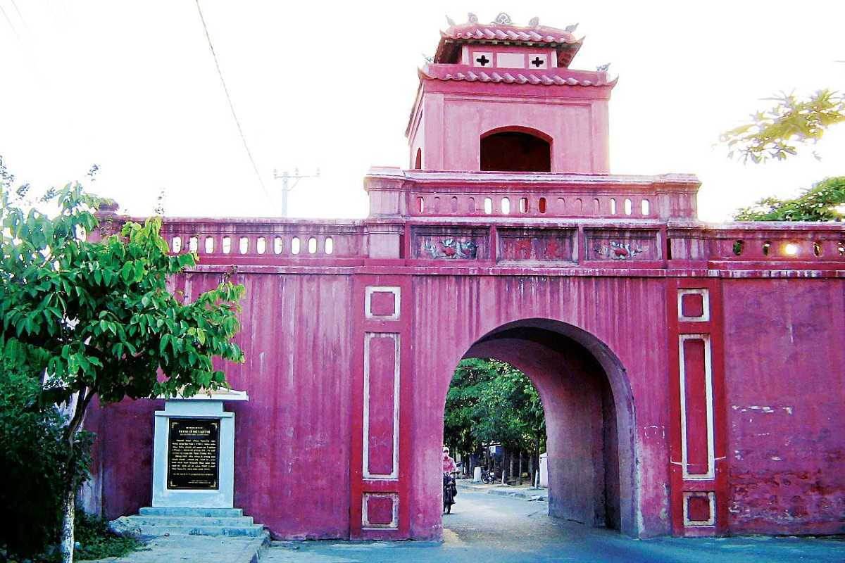 Bright image of the main arched entryway at Dien Khanh Citadel with distinct red stonework.