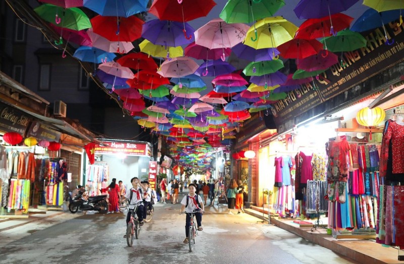 Colorful Umbrella Street in Van Phuc Silk Village at Night Colorful umbrellas hanging over the streets of Van Phuc Silk Village, with silk shops and cyclists underneath.