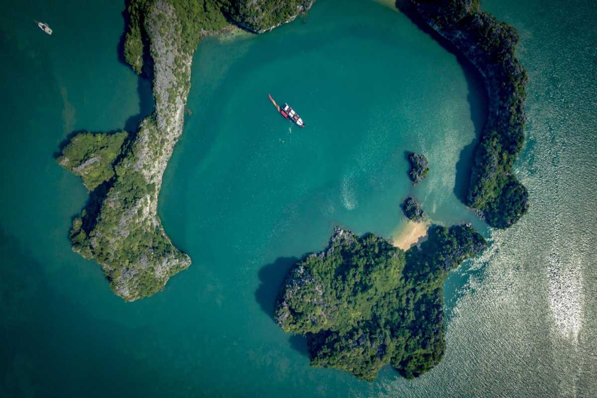 Limestone cliffs and floating houses on emerald waters at Cong Do Island Bai Tu Long Bay