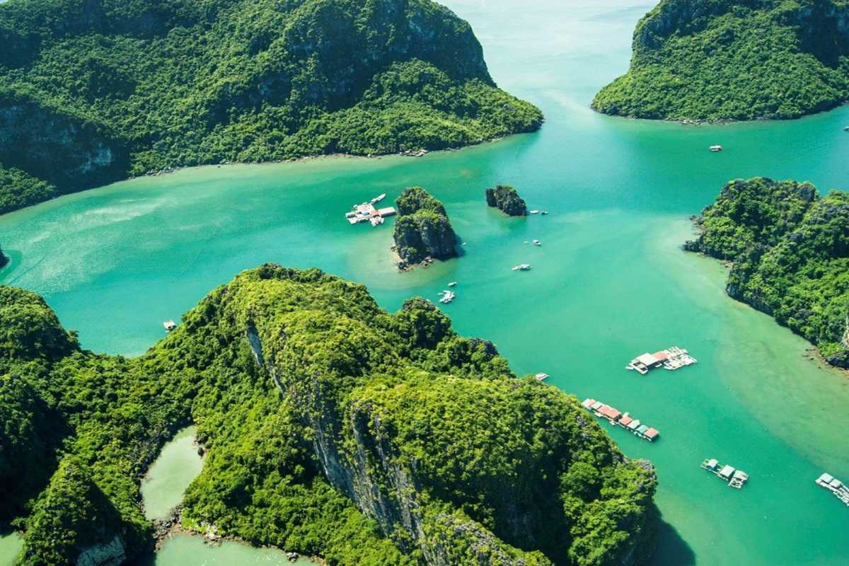 Scenic bay at Cong Do Island Bai Tu Long Bay with lush karst formations and floating houses on calm waters.