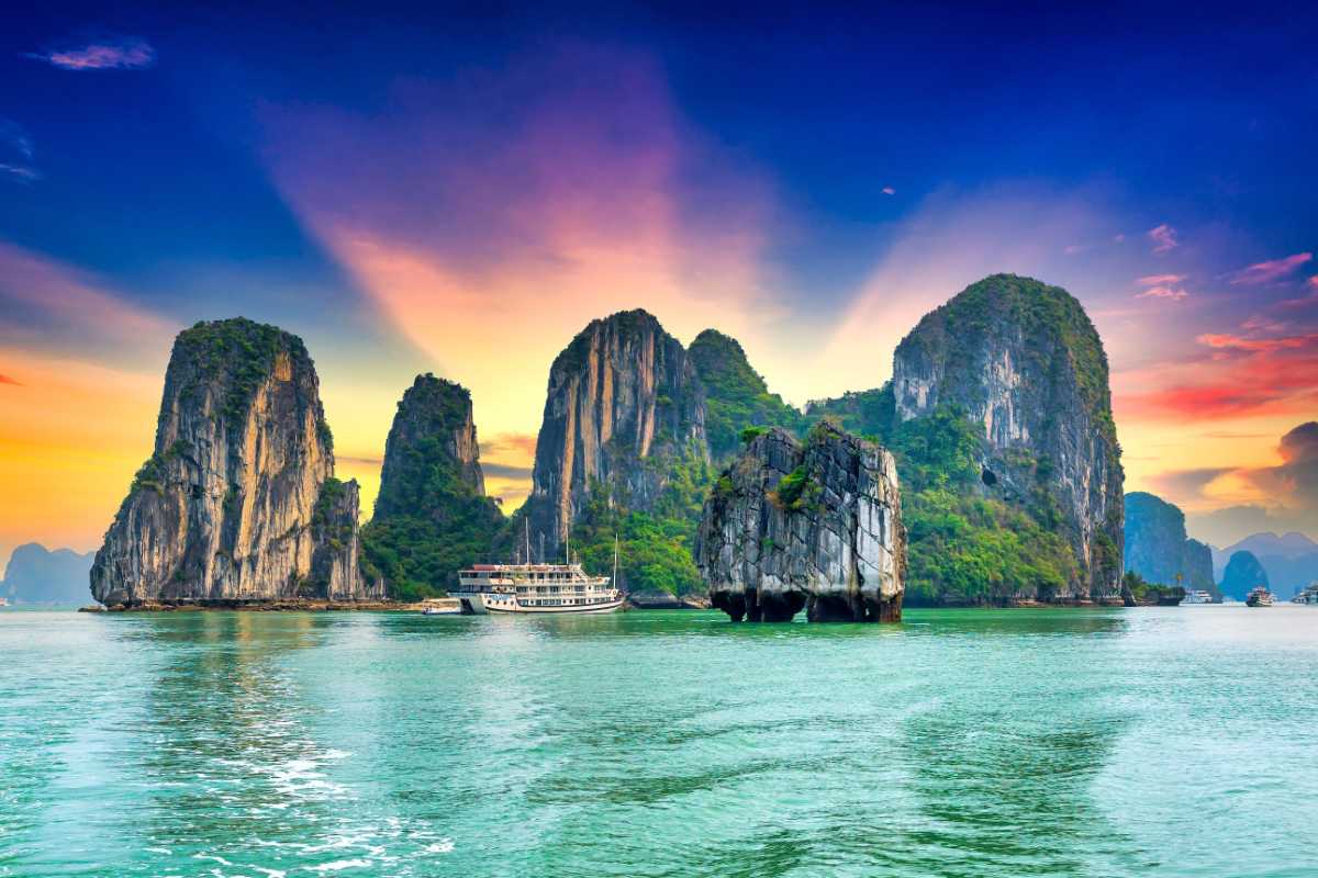 Traditional wooden boats moored near the limestone cliffs of Cong Do Island in Bai Tu Long Bay