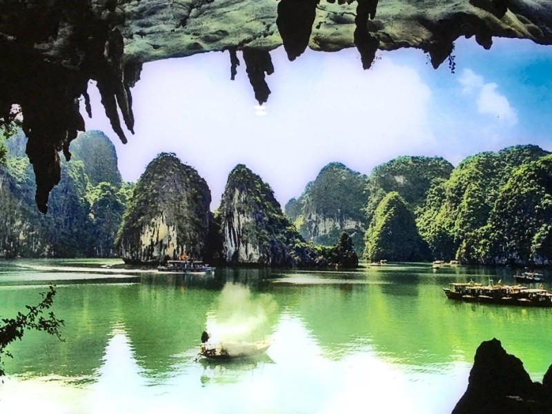 Couple standing inside Bo Nau Cave entrance A couple standing at the entrance of Bo Nau Cave, with Halong Bay's limestone islands visible in the distance.