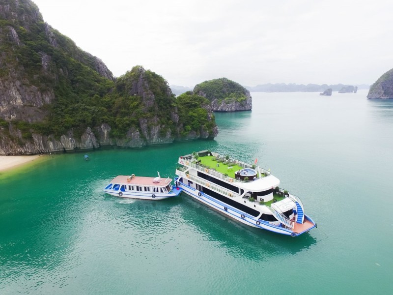 Cruise Through Ba Ham Lake in Lan Ha Bay A cruise boat traveling through the serene waters of Ba Ham Lake in Lan Ha Bay with towering cliffs in the background.