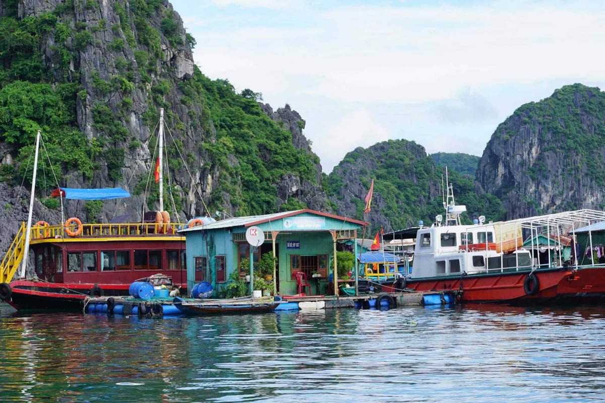 Tourists enjoying a boat ride in Cua Van Floating Village Halong Bay with lush greenery in the background