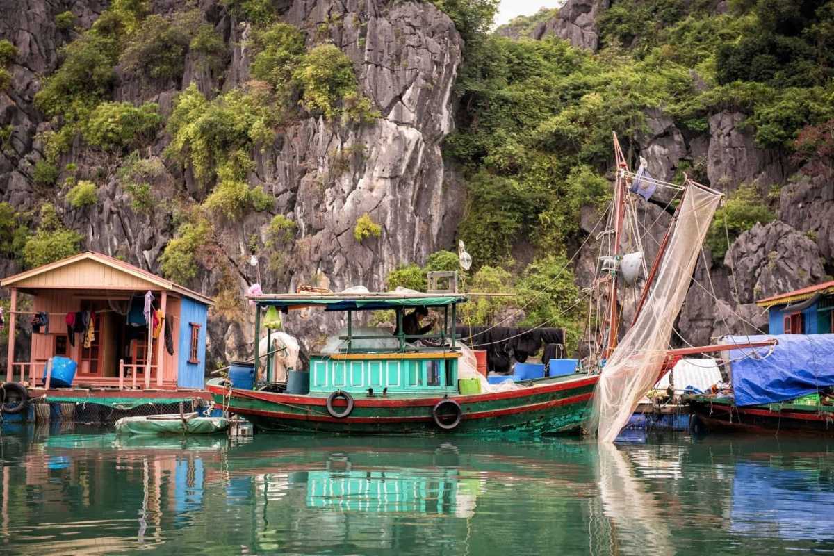 Community center and boats on floating platforms at Cua Van Floating Village Halong Bay, surrounded by limestone hills