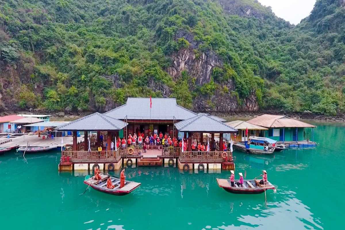 Locals engaging in daily activities on boats and floating homes at Cua Van Floating Village Halong Bay