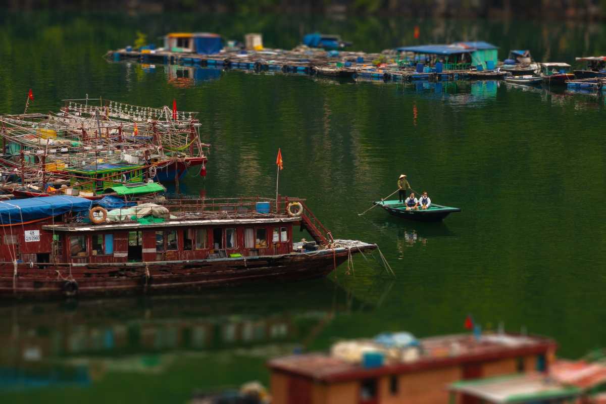 Traditional fishing boats moored in Cua Van Floating Village Halong Bay with calm waters and mountains nearby