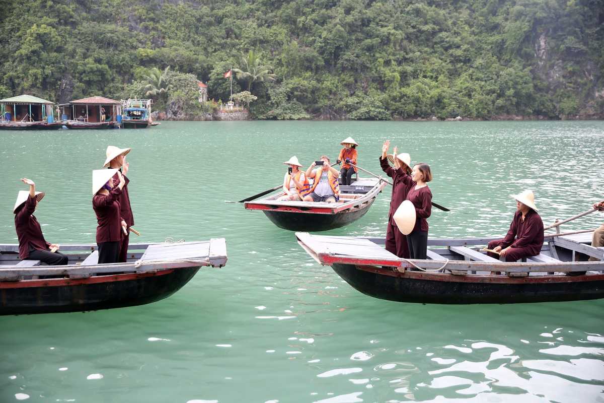 Colorful floating houses and boats nestled against towering limestone cliffs at Cua Van Floating Village Halong Bay
