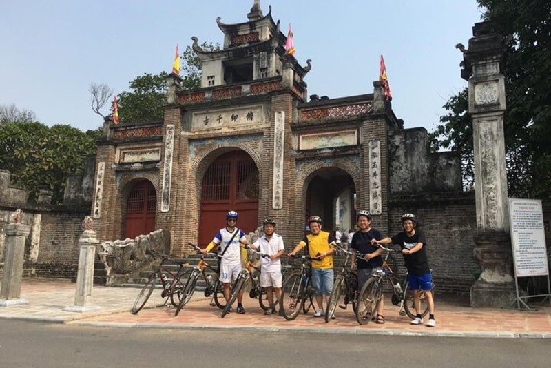Cyclists Touring Co Loa Ancient Citadel Cyclists standing at the entrance of Co Loa Ancient Citadel, preparing for a cycling tour around the historical site in Hanoi, Vietnam